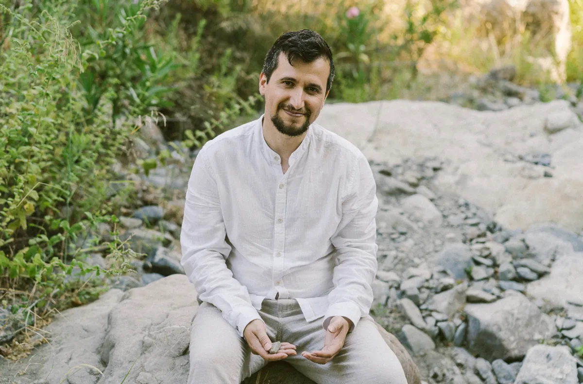Fran Pavón sentado sobre una roca en un paraje natural